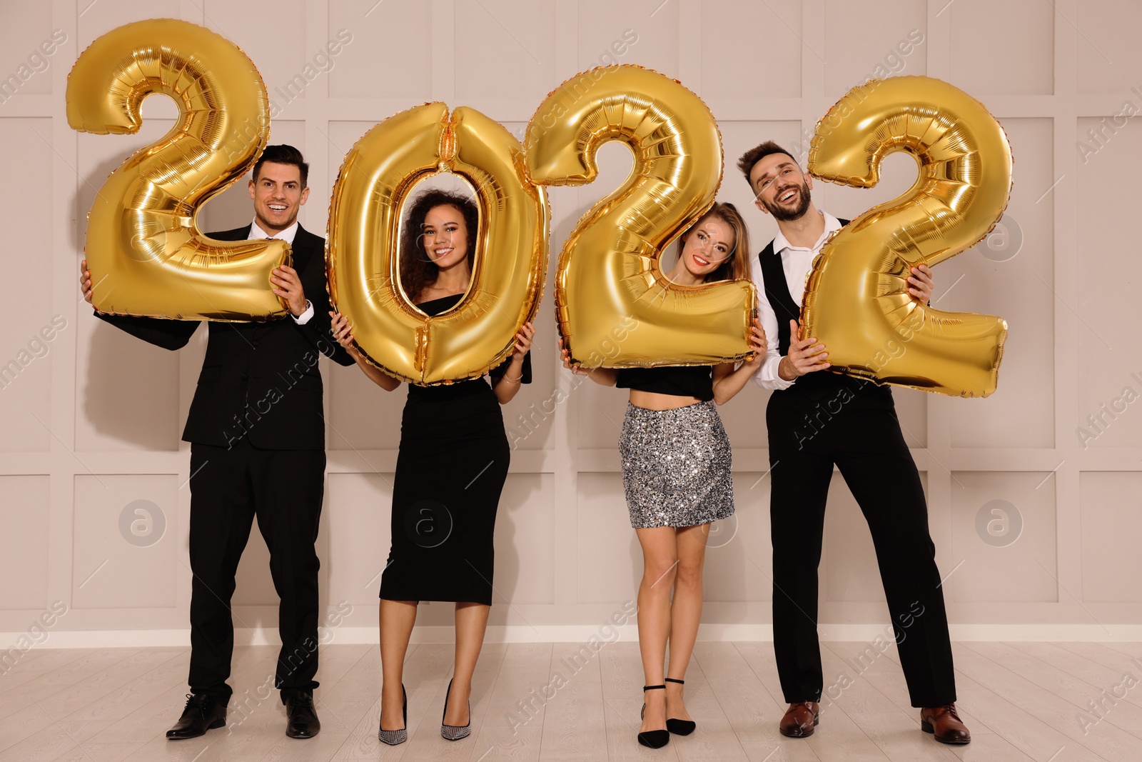 Photo of Happy friends with golden 2022 balloons indoors. New Year celebration