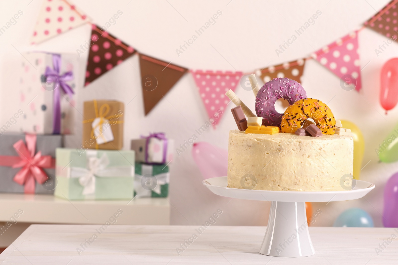 Photo of Delicious cake decorated with sweets on white wooden table in festive room, space for text