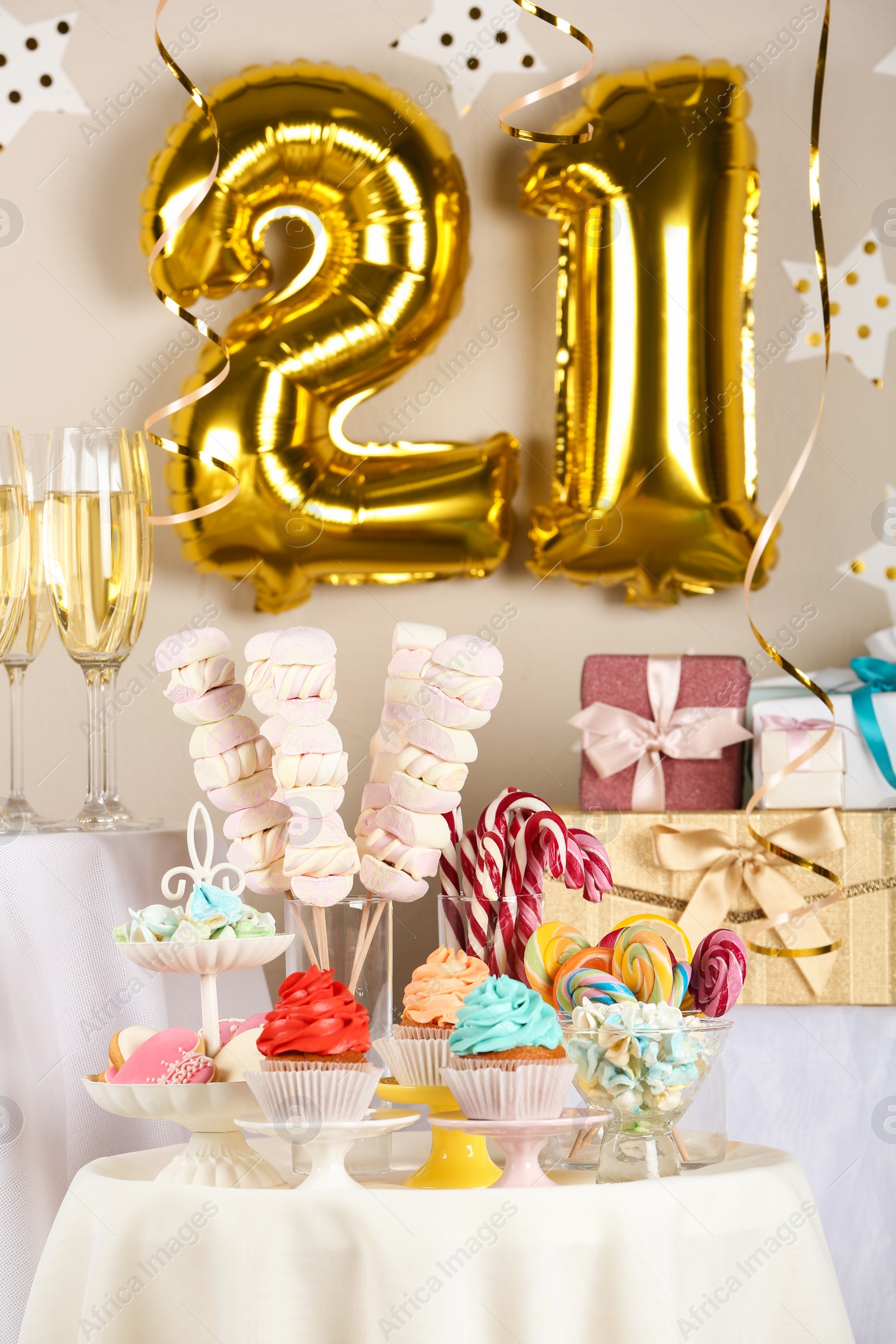 Photo of Dessert table in room decorated with golden balloons for 21 year birthday party