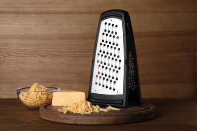 Grater and delicious cheese on wooden table