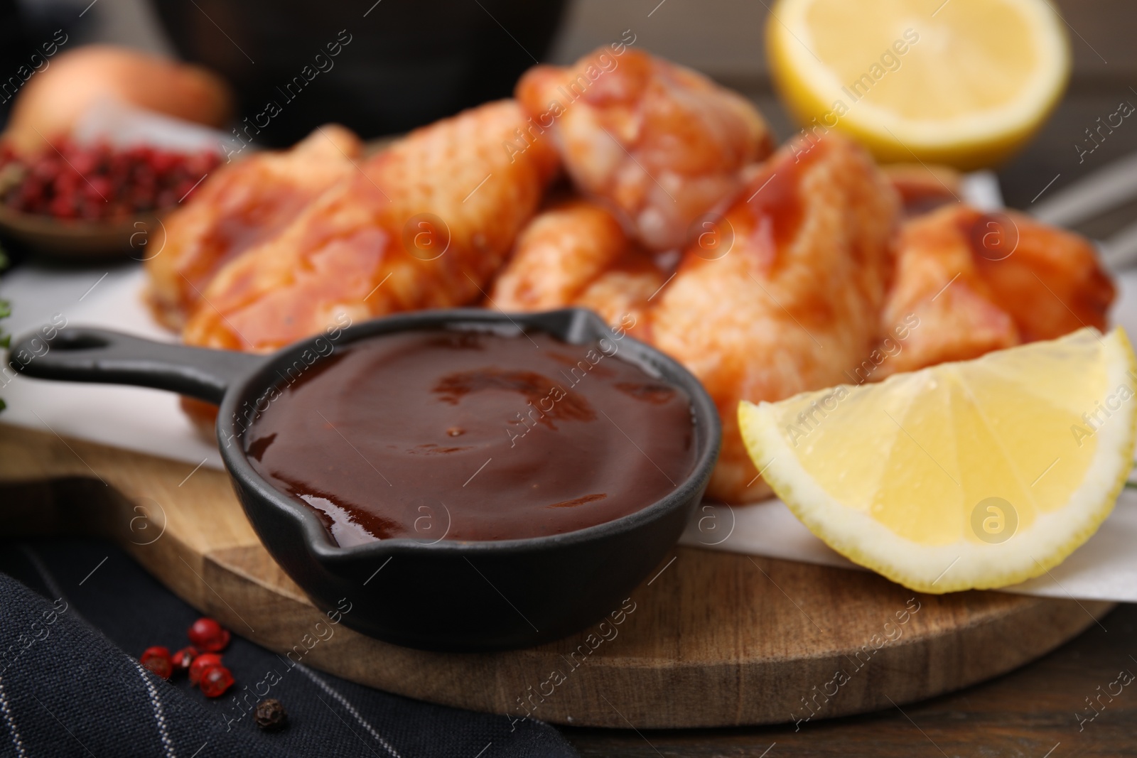 Photo of Fresh marinade, raw chicken wings and lemon on table, closeup