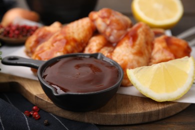 Photo of Fresh marinade, raw chicken wings and lemon on table, closeup