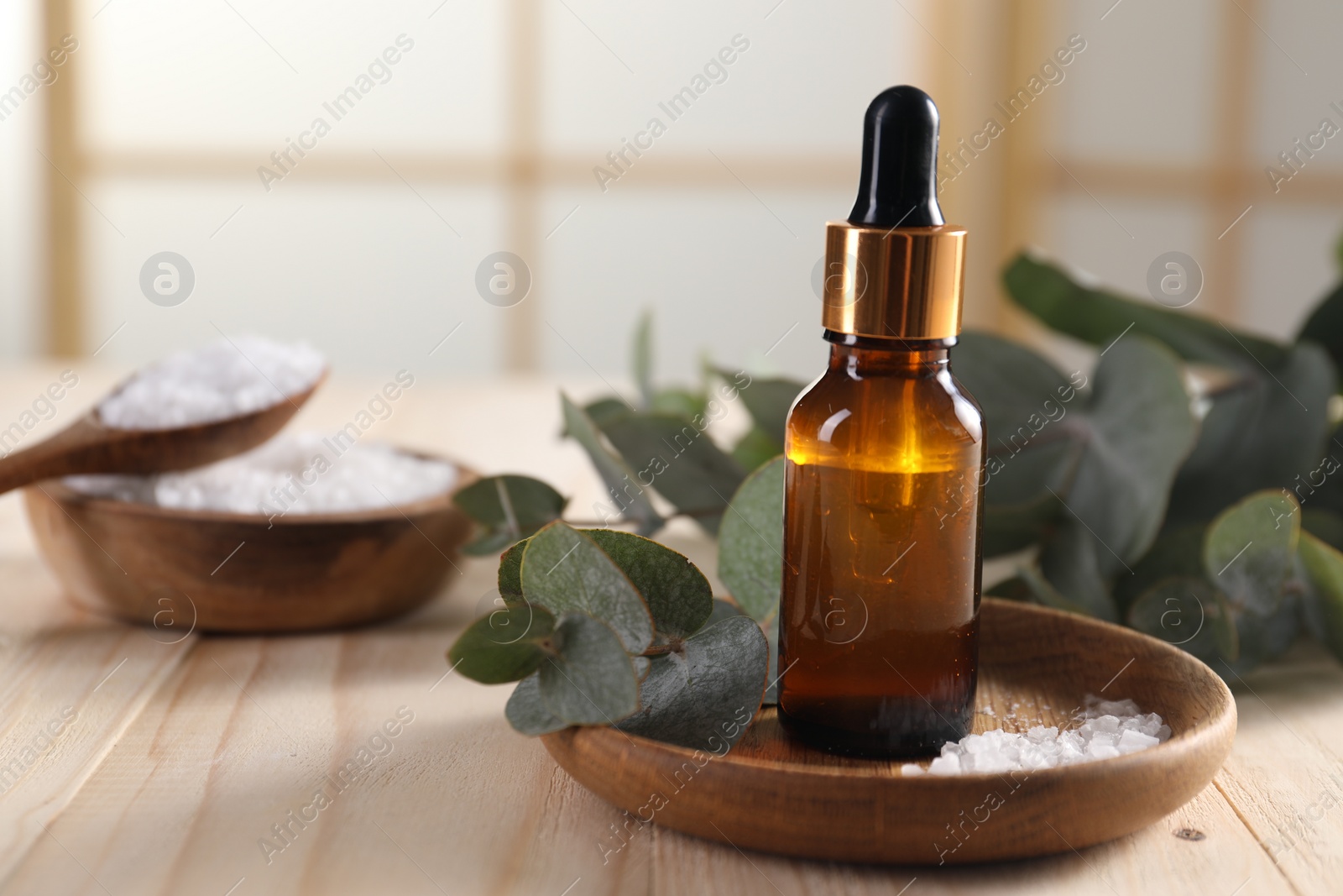 Photo of Aromatherapy. Bottle of essential oil, sea salt and eucalyptus leaves on wooden table