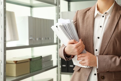 Female worker with documents in archive, closeup. Space for text