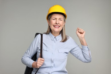 Photo of Architect in hard hat with tube on grey background