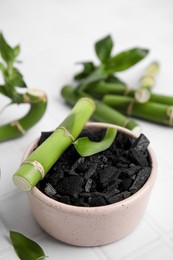 Photo of Fresh bamboo and charcoal on white tiled table, closeup