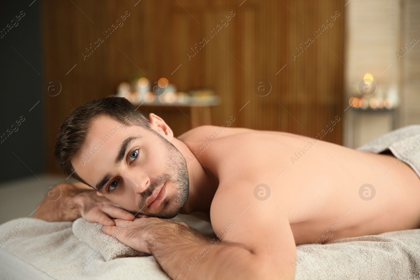 Photo of Handsome man relaxing on massage table in spa salon