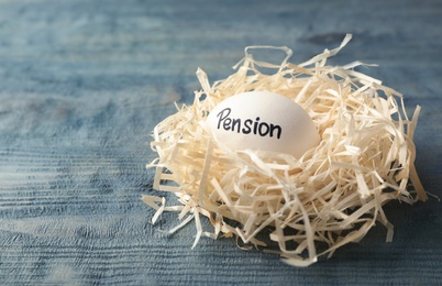 Egg with word PENSION in nest on wooden background. Space for text