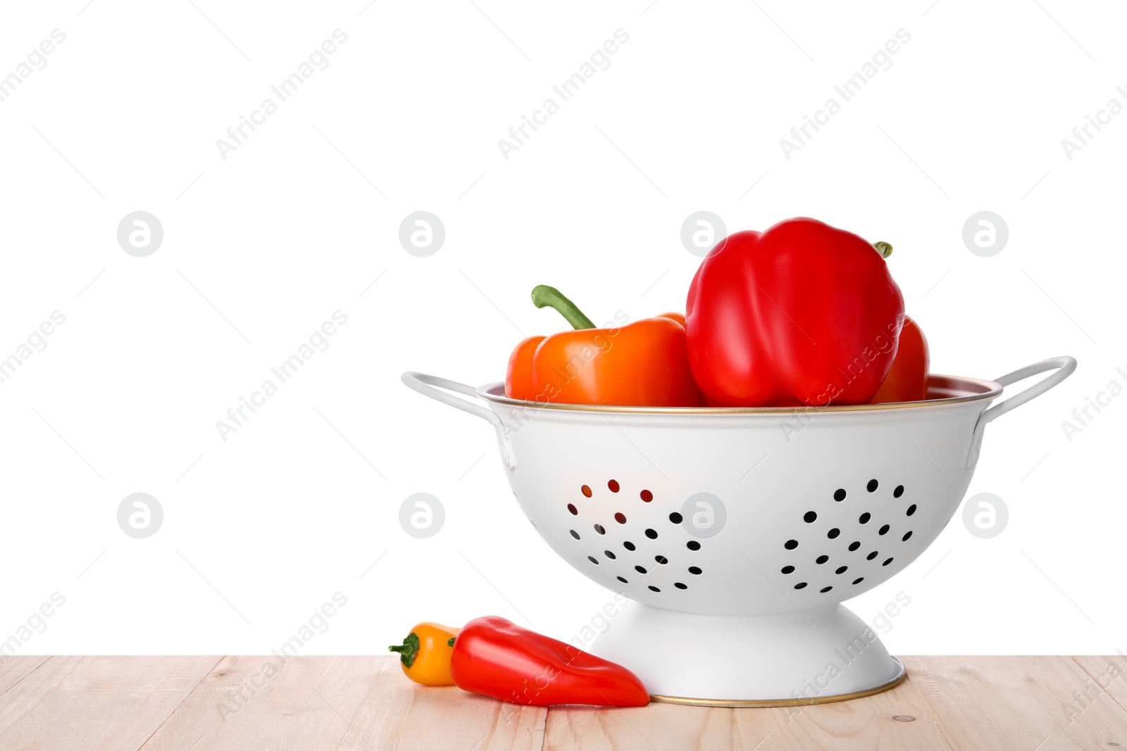 Photo of Fresh bell peppers in colander on wooden table against white background. Space for text