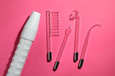 Photo of Modern darsonval with different nozzles on pink background, flat lay. Microcurrent therapy