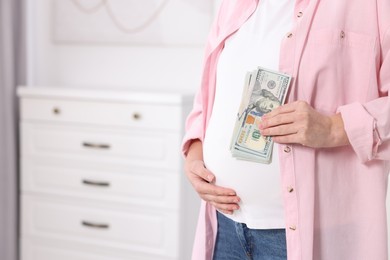 Surrogate mother. Pregnant woman with dollar banknotes indoors, closeup. Space for text