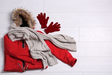 Photo of Flat lay composition with warm clothes for winter vacation on wooden background. Space for text