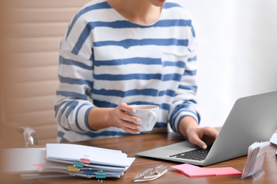 Photo of Young journalist working with laptop in office, closeup