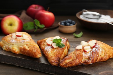 Photo of Fresh tasty puff pastry with apples and mint served on wooden table, closeup
