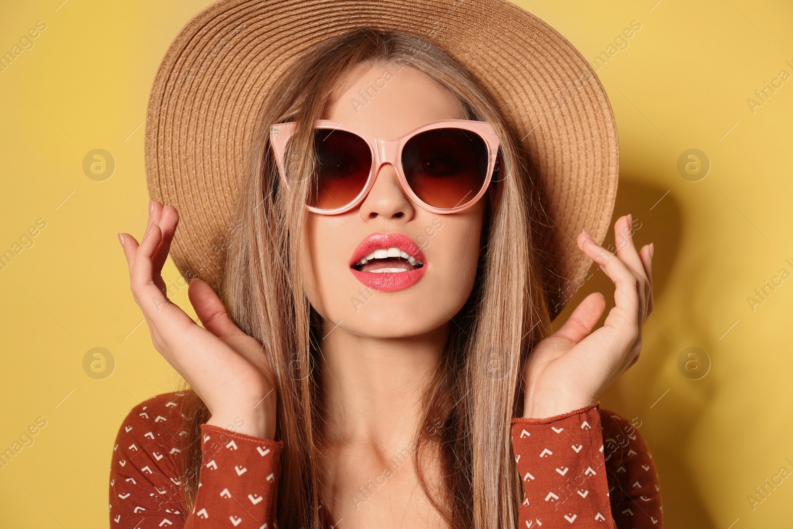 Photo of Young woman wearing stylish sunglasses and hat on yellow background