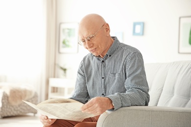 Elderly man reading newspaper in living room