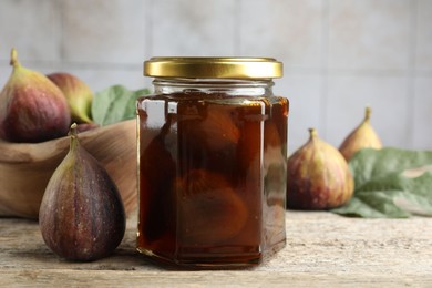 Jar of tasty sweet jam and fresh figs on wooden table