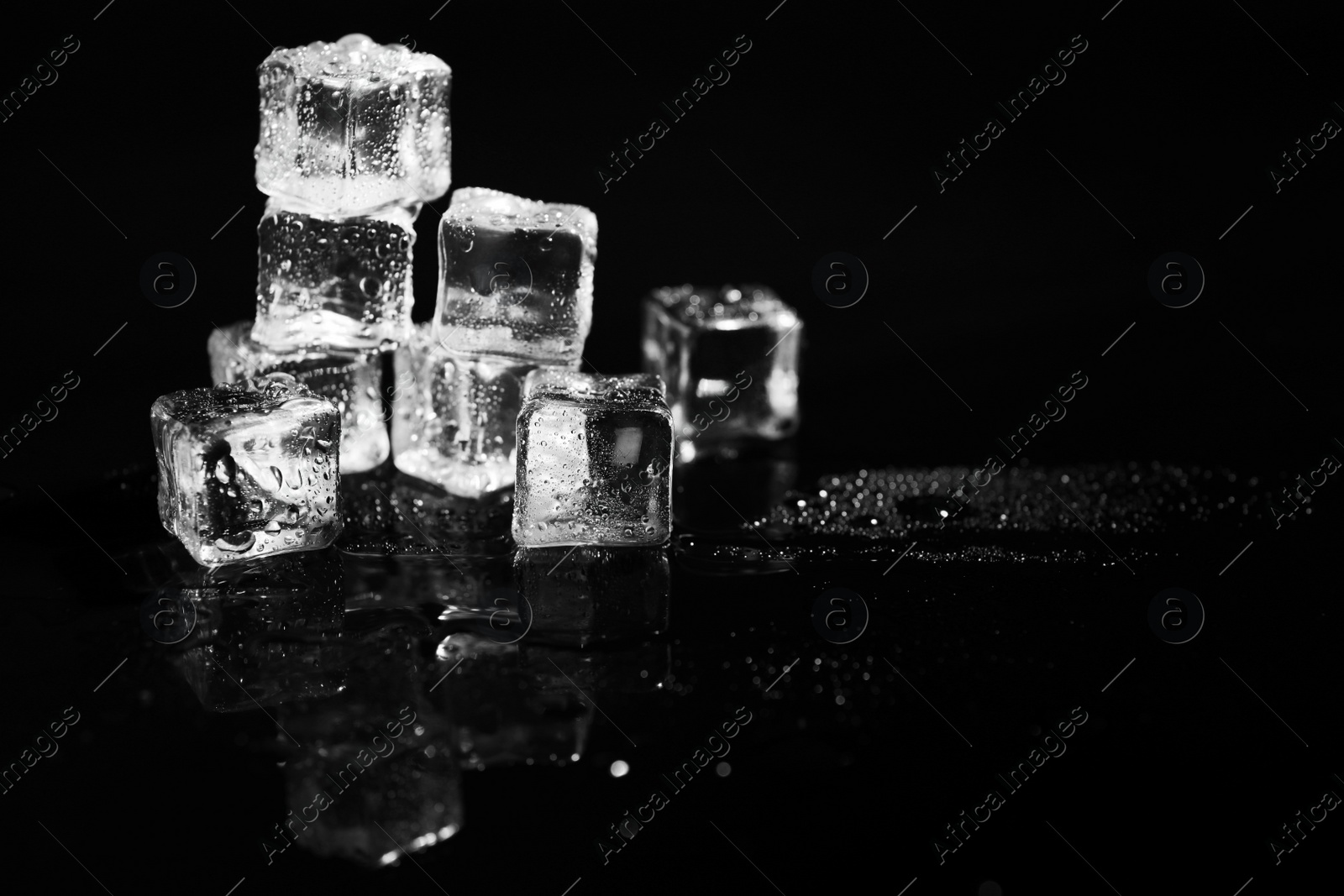 Photo of Pile of crystal clear ice cubes on black background. Space for text