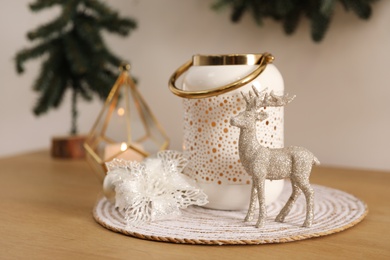 Small shiny deer, decorative flower and candle holder on wooden table. Interior design