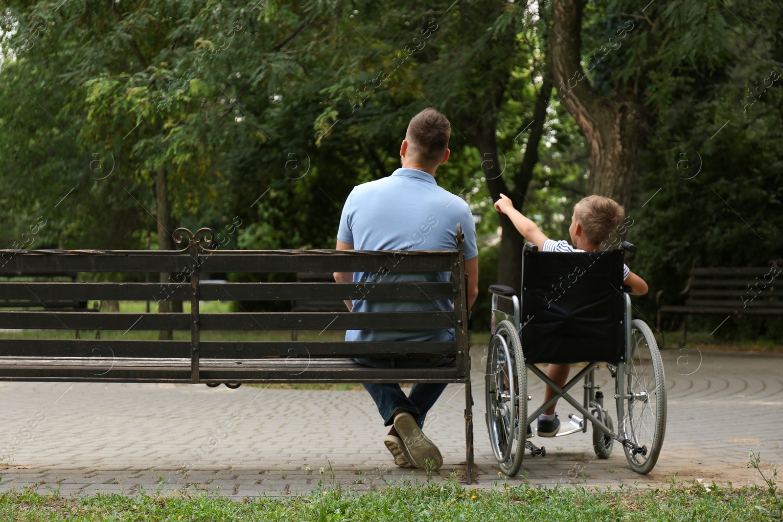 Photo of Father with his son in wheelchair at park