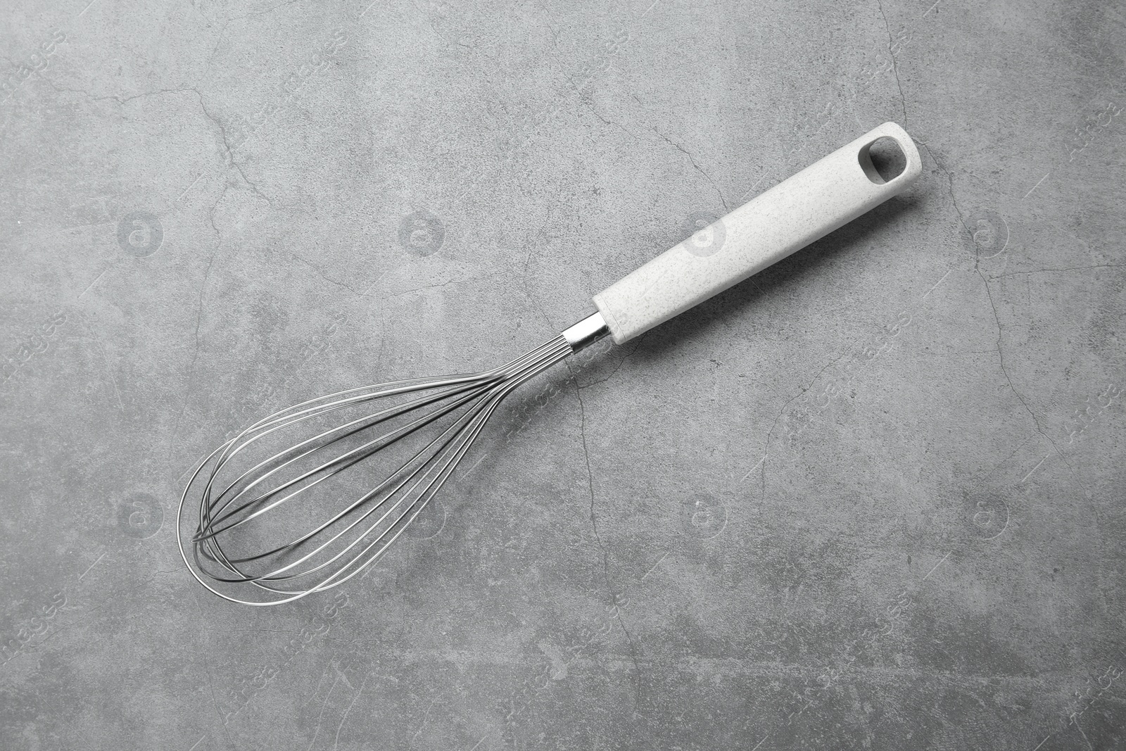 Photo of Metal whisk on gray table, top view