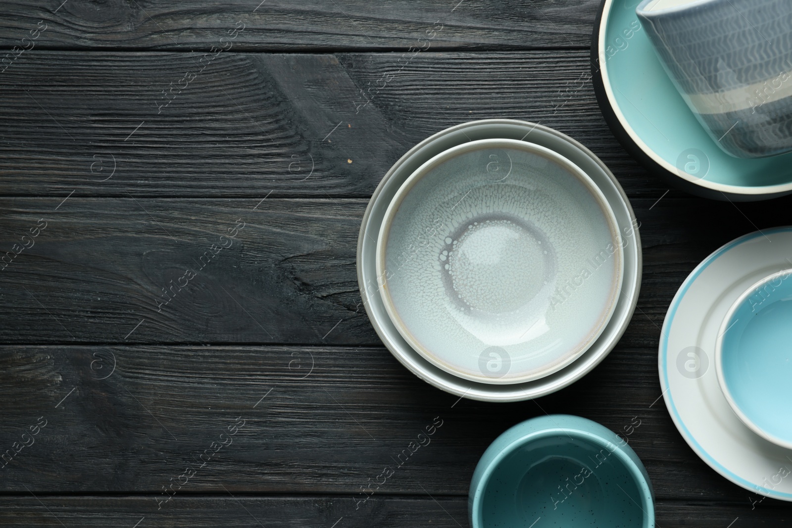 Photo of Stylish empty dishware on black wooden table, flat lay. Space for text