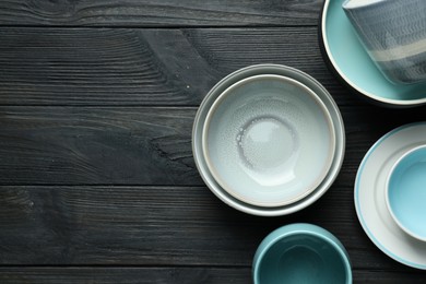 Stylish empty dishware on black wooden table, flat lay. Space for text