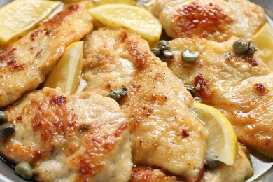 Photo of Delicious chicken piccata with lemons in pot, closeup