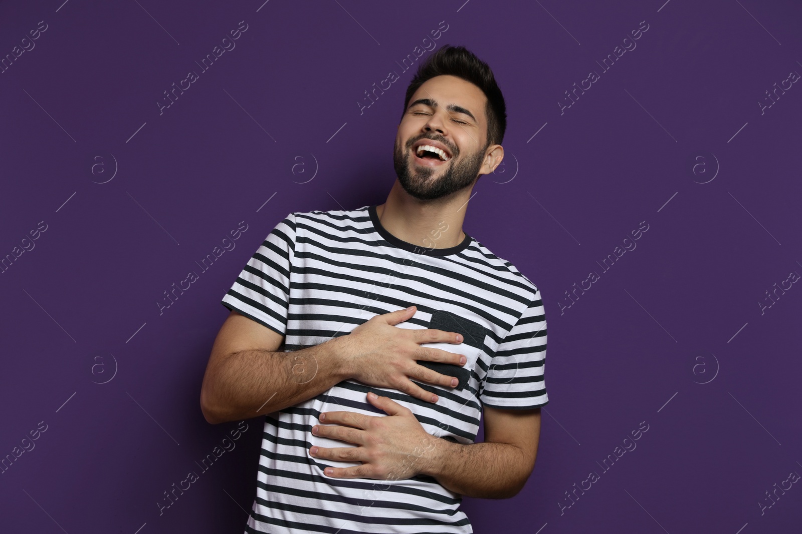 Photo of Young man laughing on purple background. Funny joke