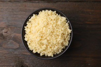 Tasty couscous in bowl on wooden table, top view