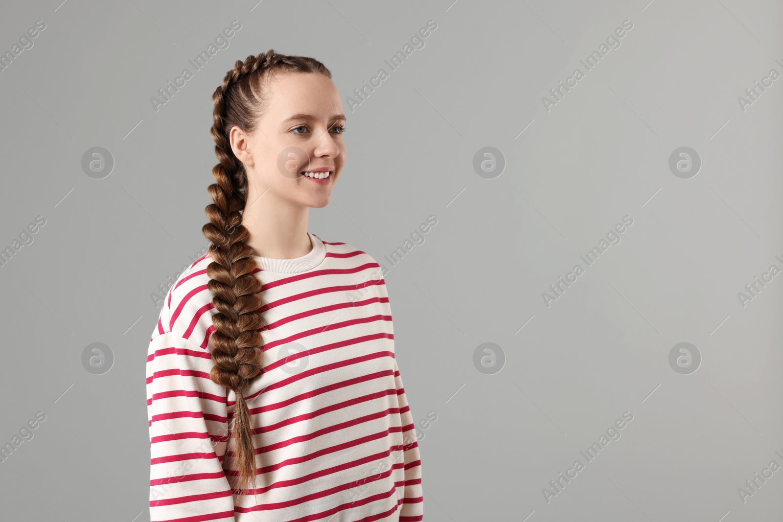 Photo of Woman with braided hair on grey background, space for text