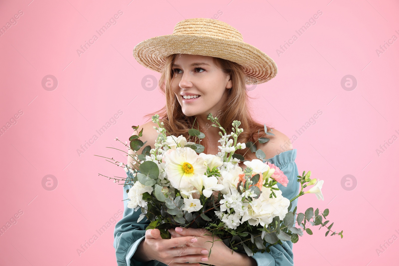 Photo of Beautiful woman in straw hat with bouquet of flowers on pink background