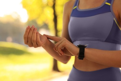 Photo of Woman checking pulse after training in park on sunny day. closeup