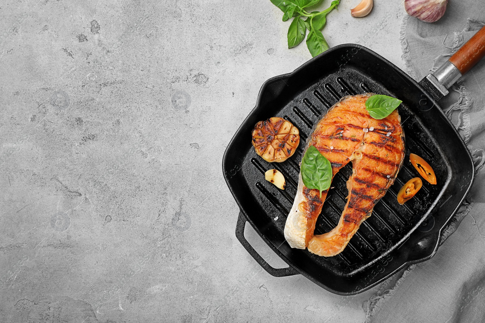 Photo of Frying pan with tasty salmon steak on grey background