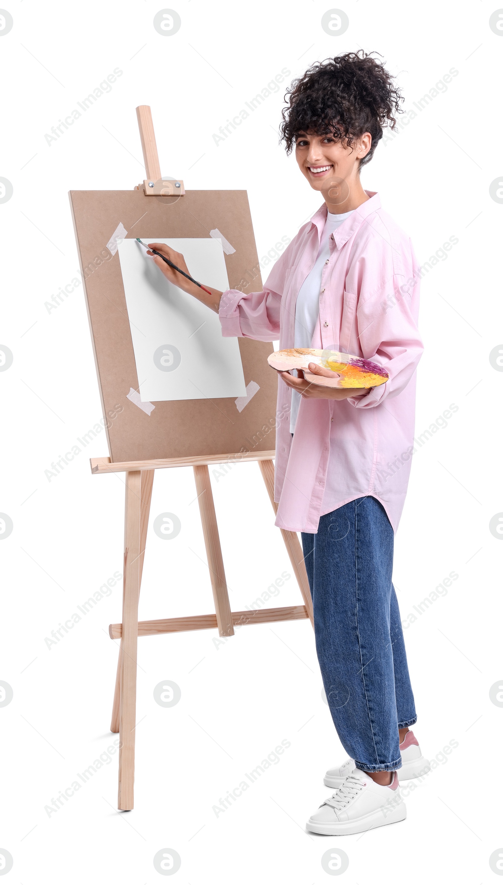 Photo of Young woman painting on easel with paper against white background