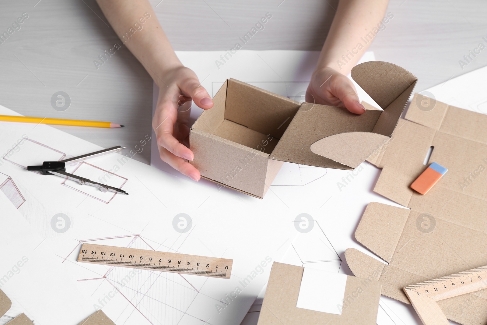 Photo of Woman creating packaging design at light wooden table, closeup