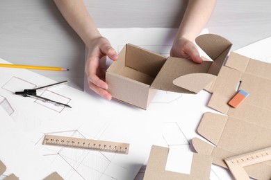 Woman creating packaging design at light wooden table, closeup