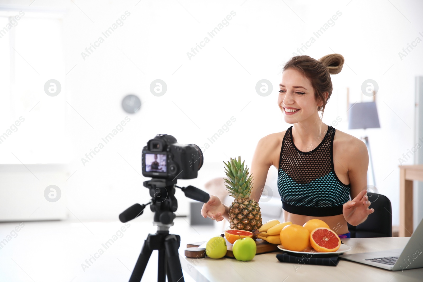 Photo of Young blogger with fruits recording video on kitchen