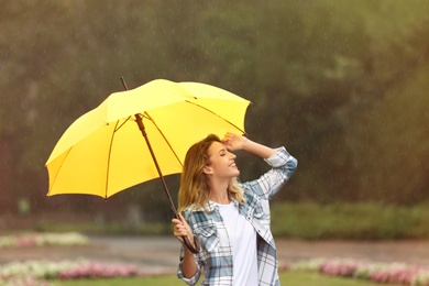 Happy young woman with umbrella under rain in park