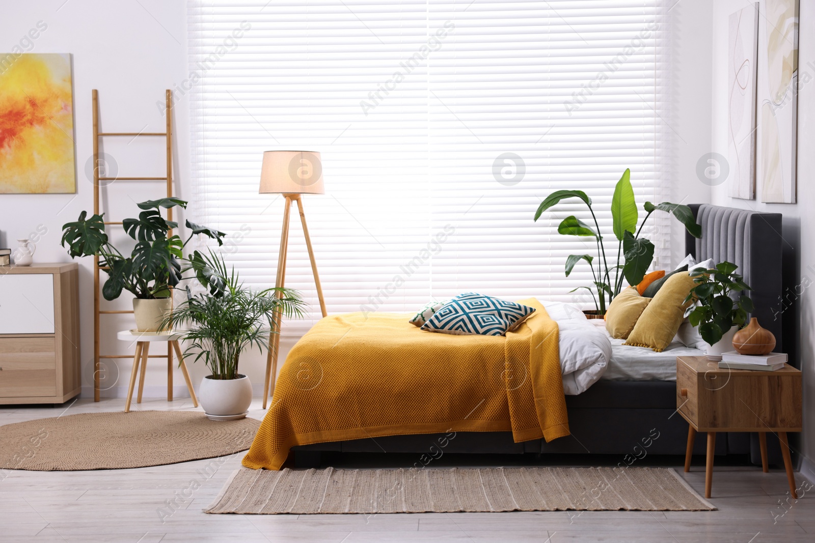 Photo of Bright plaid and colorful pillows on bed in stylish bedroom. Interior design