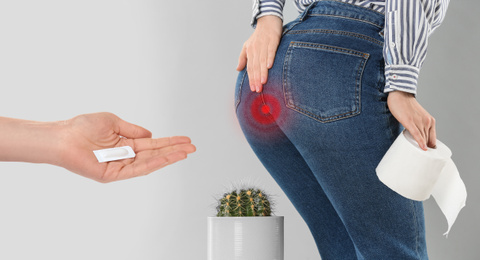 Image of Doctor holding suppository for hemorrhoid treatment and woman suffering from pain on light background, closeup