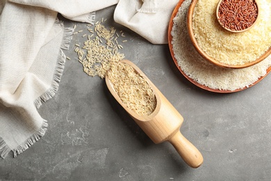 Flat lay composition with brown and other types of rice on grey background