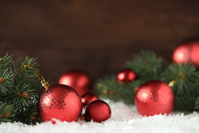 Photo of Beautiful Christmas balls and fir branches on snow. Space for text