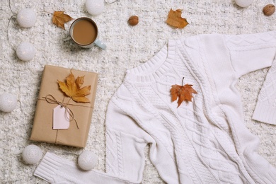 Photo of Flat lay composition with warm sweater on light fabric