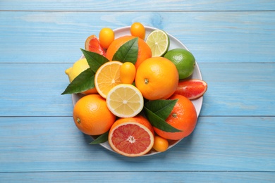 Photo of Different citrus fruits on light blue wooden table, top view