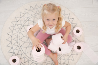 Cute little girl playing with toilet paper in bathroom