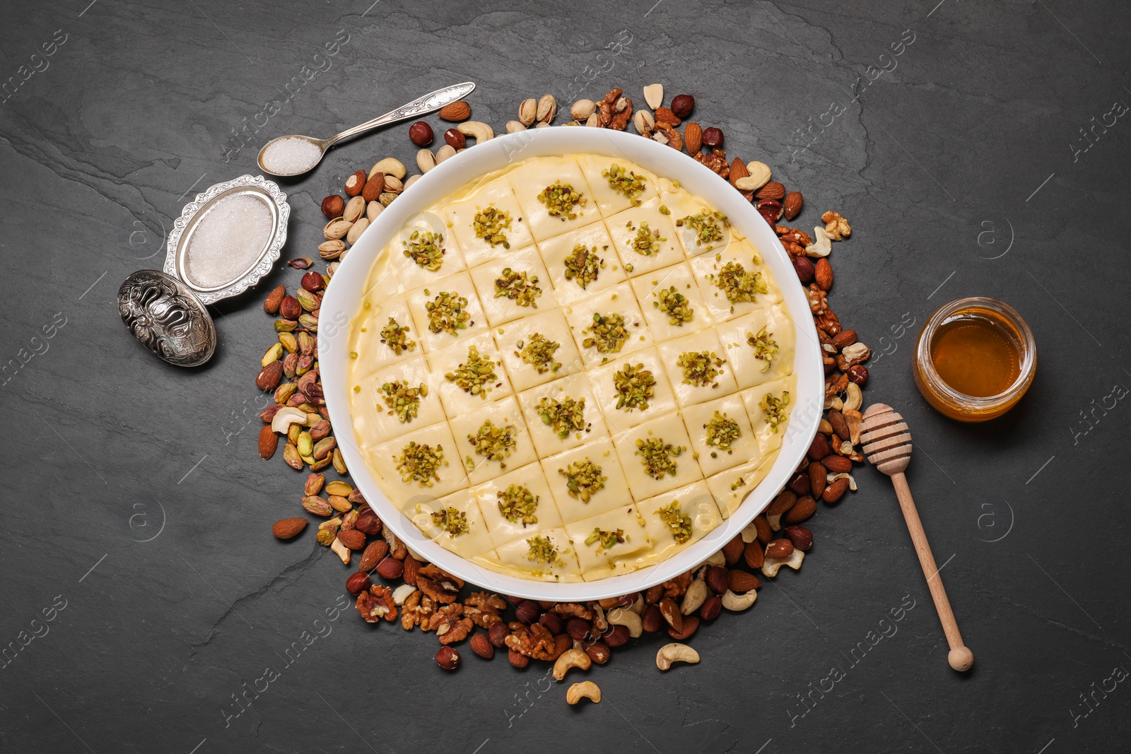 Photo of Making delicious baklava. Raw dough with different nuts on black textured table, flat lay