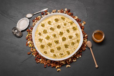 Making delicious baklava. Raw dough with different nuts on black textured table, flat lay