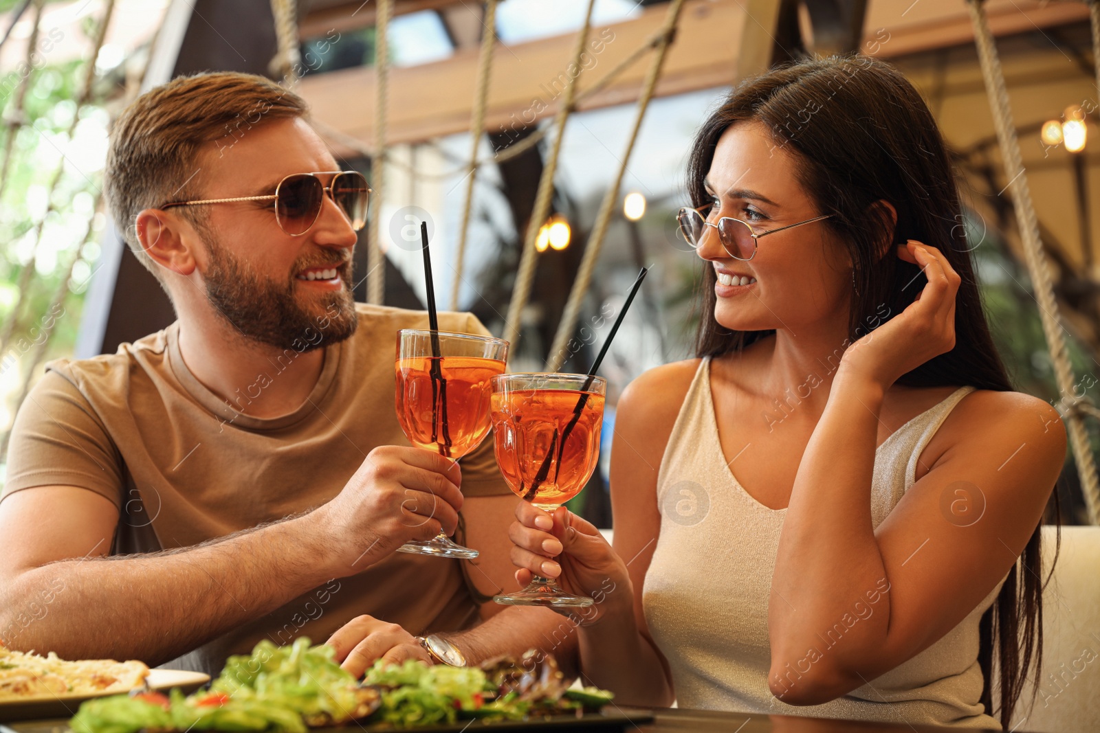 Photo of Lovely couple with Aperol spritz cocktails resting together at restaurant