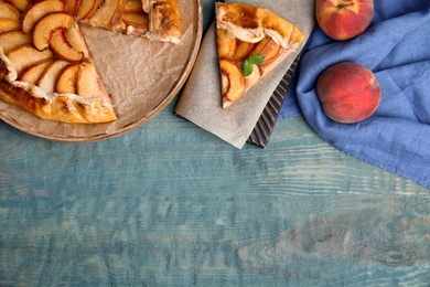 Photo of Delicious fresh peach pie on blue wooden table, flat lay. Space for text